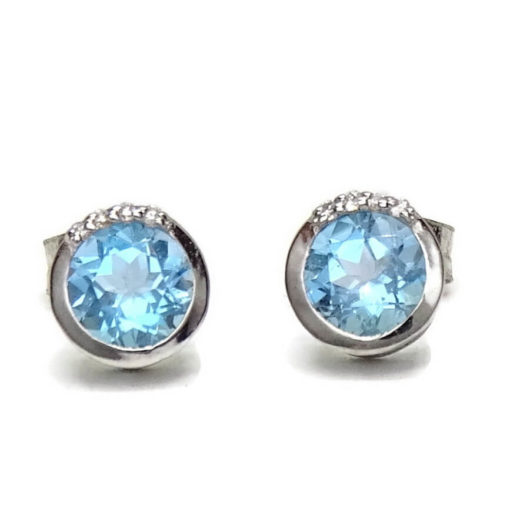 Preciosos y vistosos pendientes de oro blanco de 18k con 8 diamantes que suman 0.04cts y 2 topacios azules. Tamaño del pendientes; 6mm de diámetro y cierre presión.